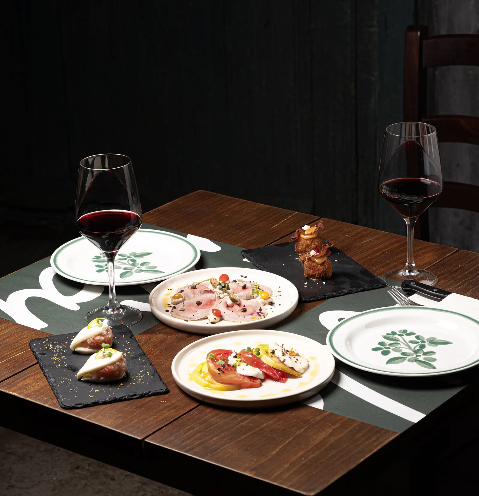 Mesa de A’Napule con varios entrantes para compartir y dos copas de vino tinto