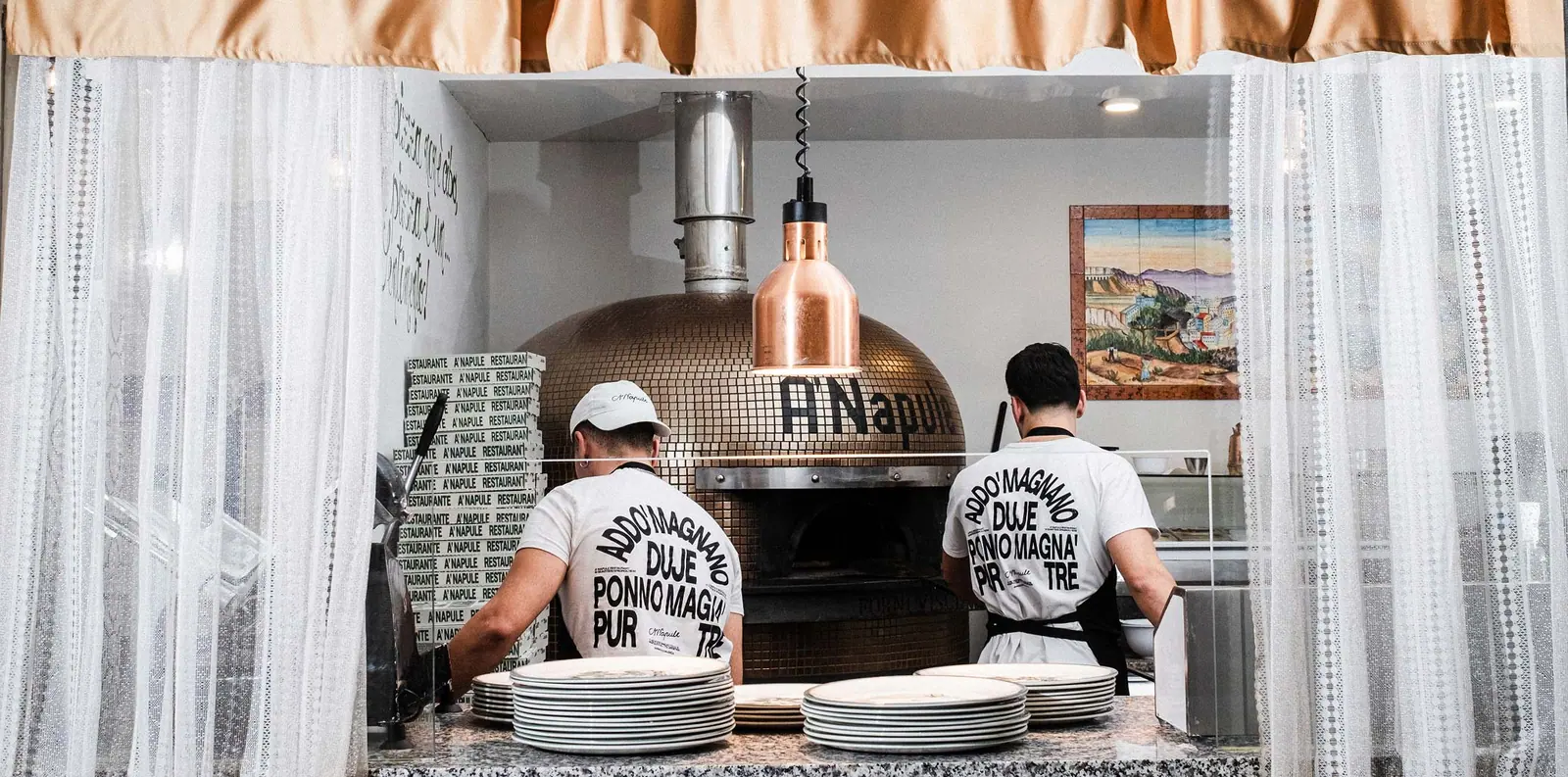 Dos pizzaioli trabajando junto al horno de A’Napule