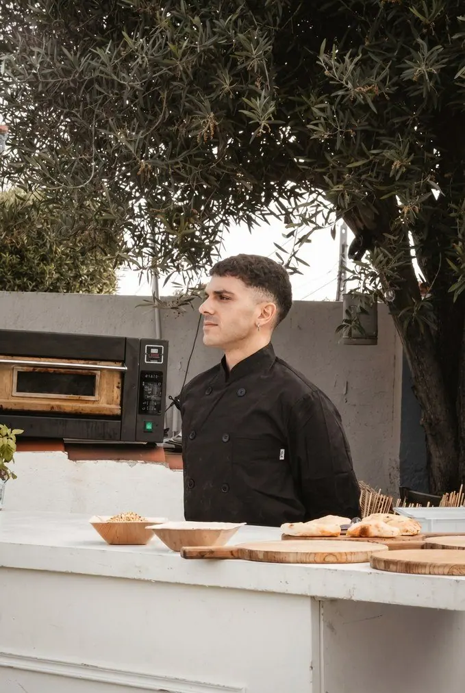 Cocinero de catering junto al horno de pizza