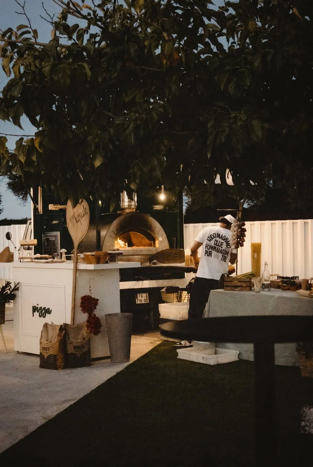 Puesto de pizzas con horno en el jardín de una celebración