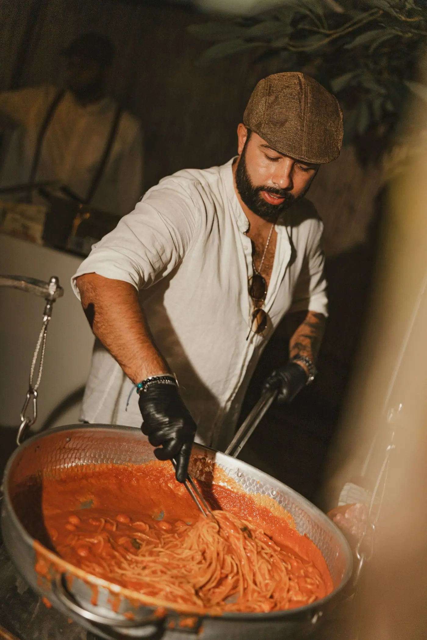 Cocinero removiendo la pasta en una sartén durante el catering