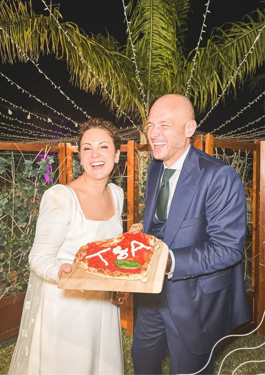 Una pareja sonríe mientras sostiene una pizza en su celebración