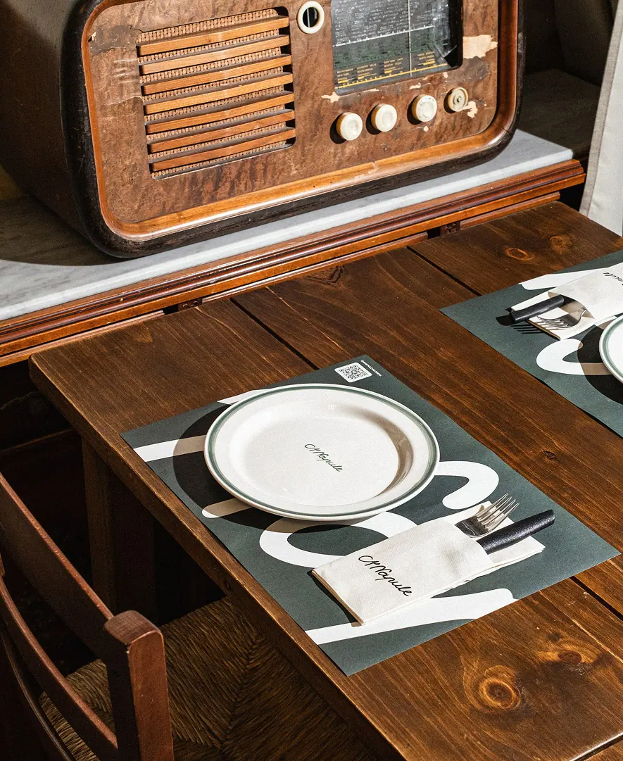 Mesa de madera preparada con plato blanco, cubiertos y mantel individual de A’Napule